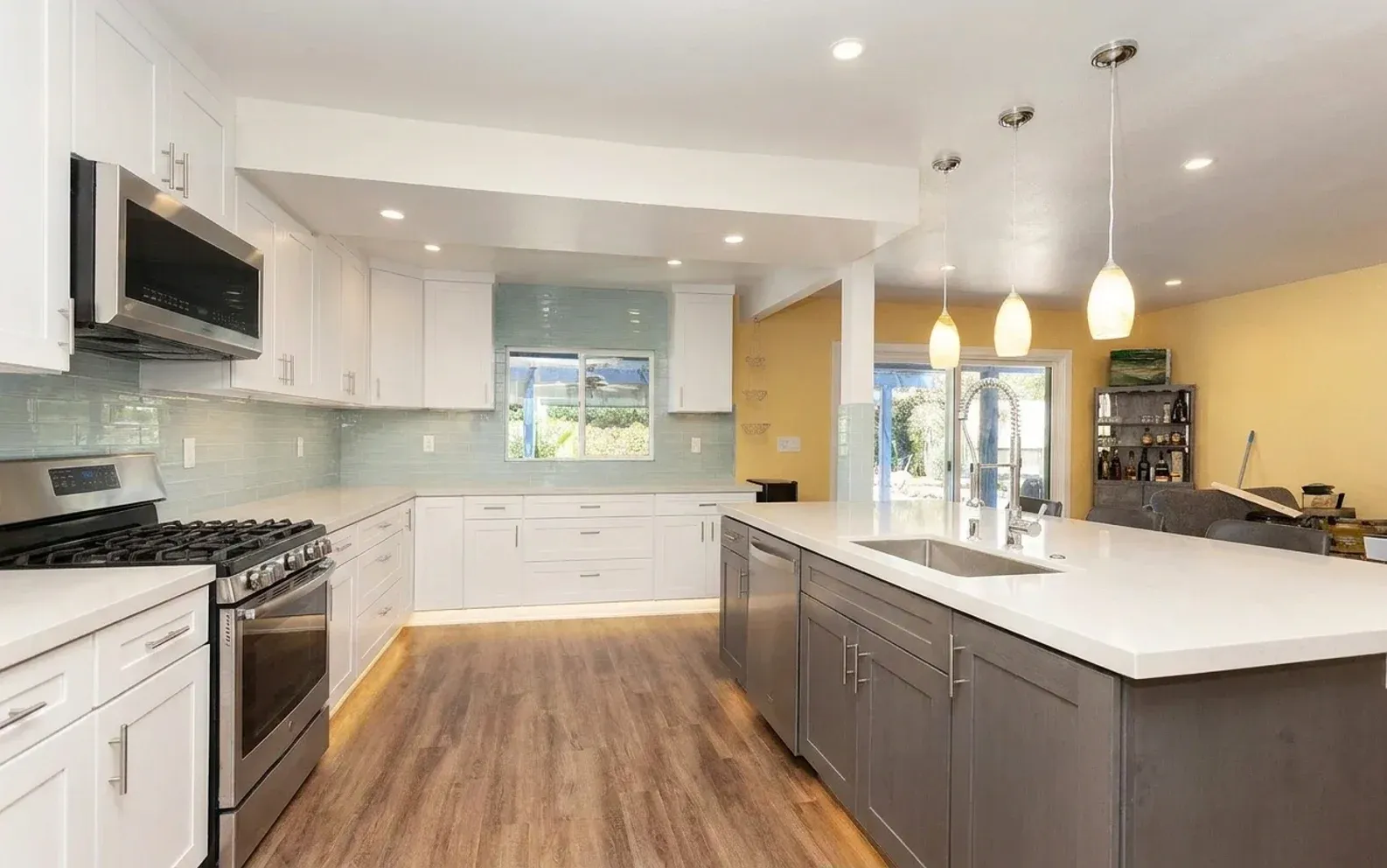 A renovated kitchen with a grey island and white cabinetry
